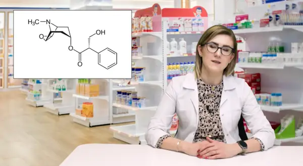 Schemat cząsteczki scopolanu, leku stosowanego m.in. w chorobie lokomocyjnej, obok farmaceutki w aptece.