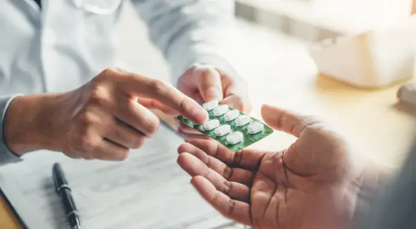 Lekarz podaje pacjentowi opakowanie tabletek. Sprawdź aktualną xarelto 20 mg cena.