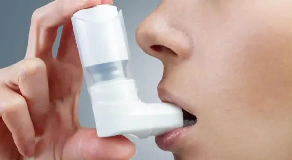 Dłoń trzyma inhalator Ventolin przy ustach. Szybka pomoc w trudnych chwilach.