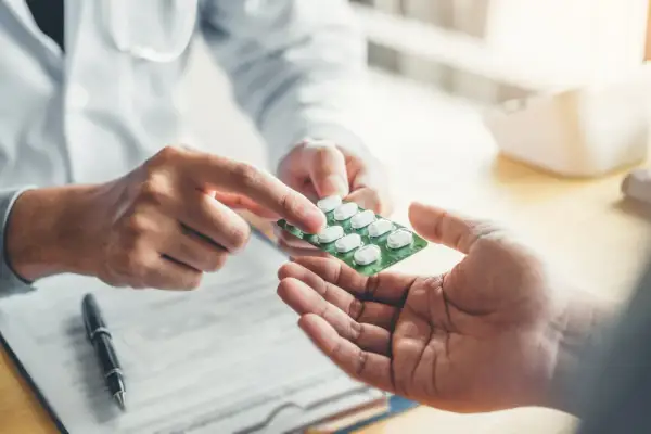 Lekarz podaje pacjentowi opakowanie tabletek. Sprawdź aktualną xarelto 20 mg cena.